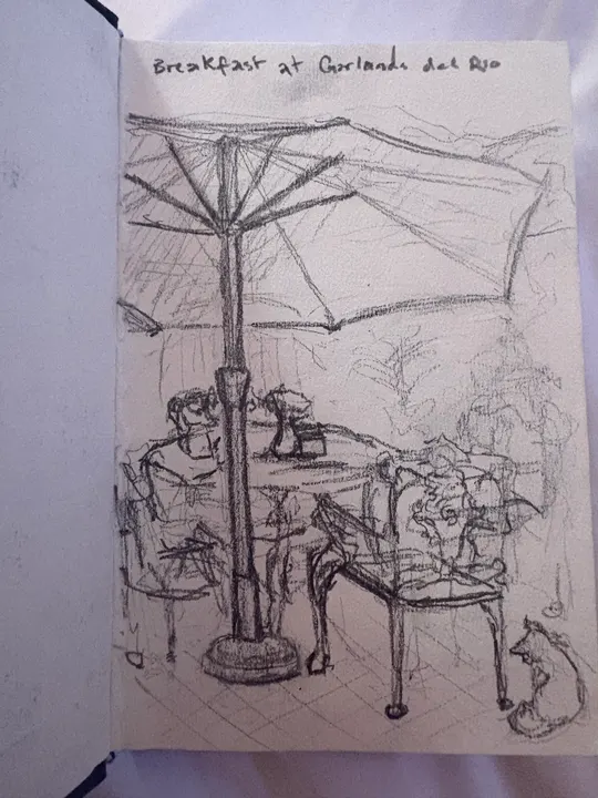 Pencil sketchbook page of a café terrace under a large parasol, chairs and plants, a cat sitting in the corner