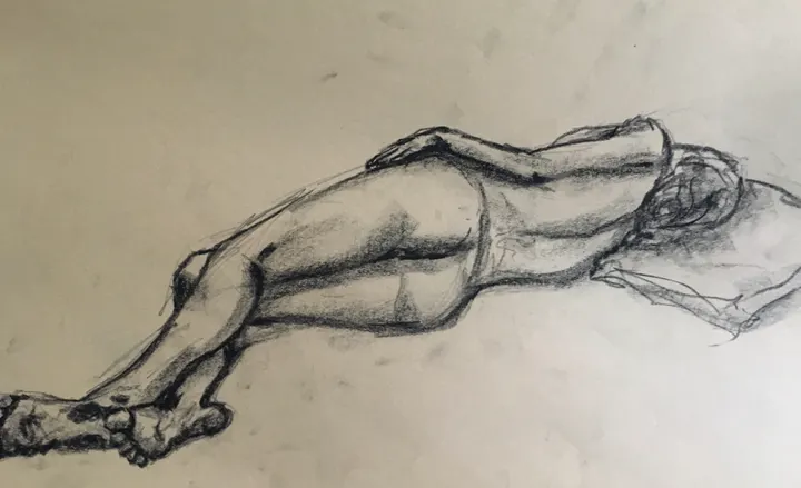 Charcoal life drawing of a nude figure lying face down