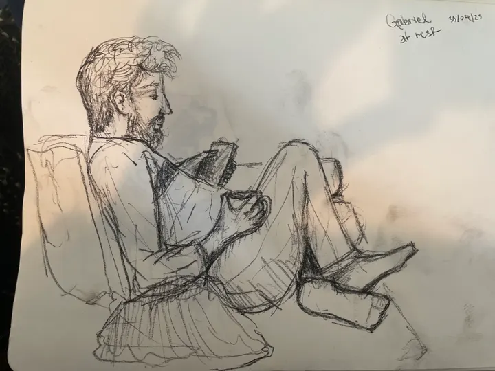 Pencil sketch of a bearded man reclining with his knees up, looking at his phone