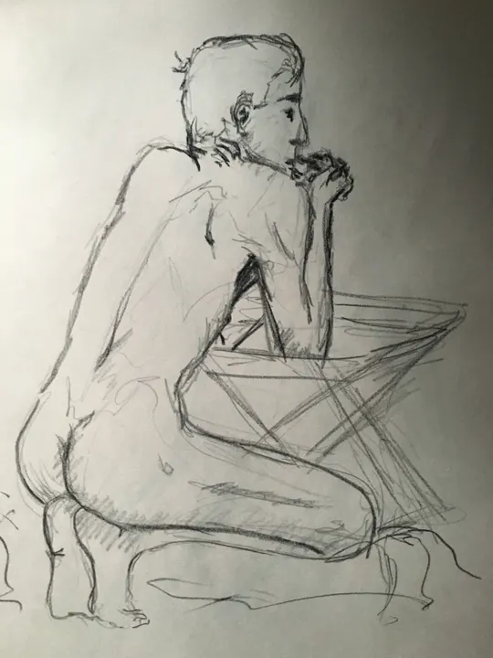 Charcoal life drawing of a seated nude figure leaning forward, seen from behind