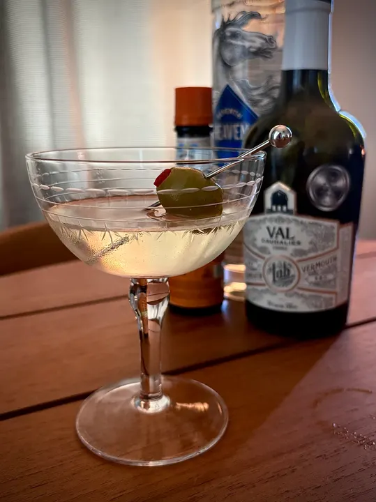 The martini beside a bottle of vermouth