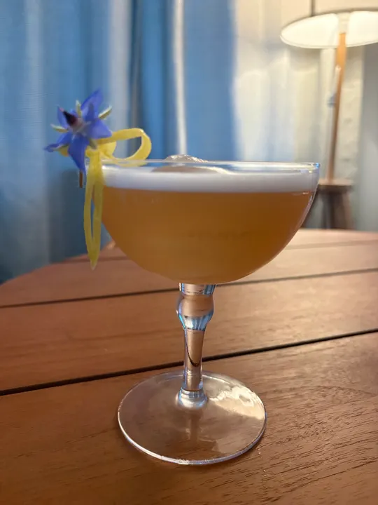 A version without the ice sphere: golden sour in a coupe with borage and a lemon twist