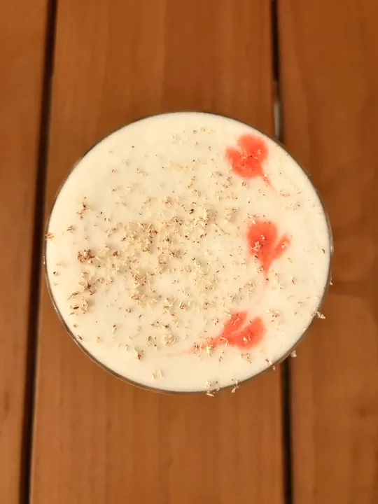 Overhead of the foam: a scattering of grated nutmeg and three coral-pink Peychaud's hearts
