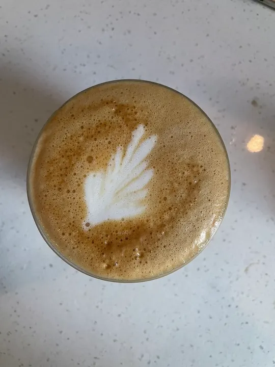 A small leaf on a latte in a glass
