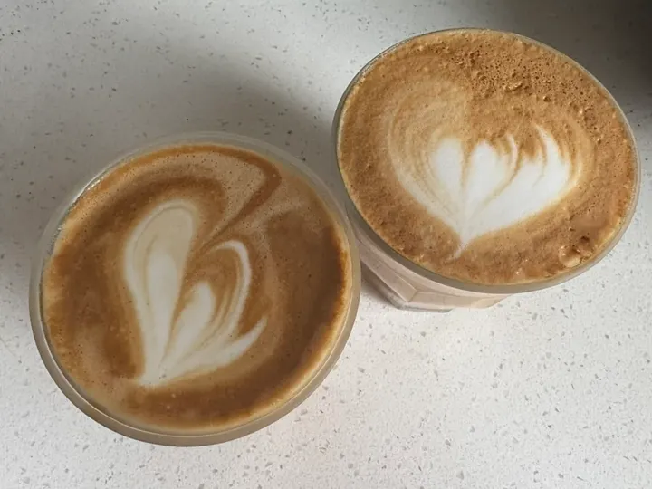 Two lattes side by side, a slanted tulip and a heart