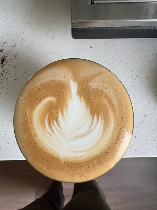 A rosetta in a glass, coffee grounds scattered on the counter