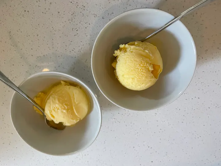 Two bowls of yellow ice cream, one softer than the other
