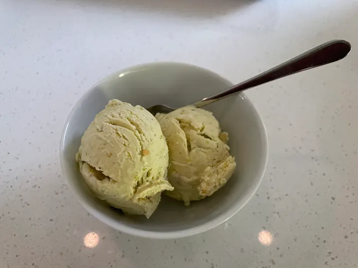 Two scoops of pale green ice cream in a white bowl