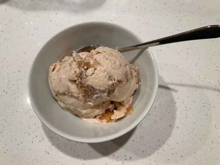 Light brown ice cream with darker ripples in a white bowl