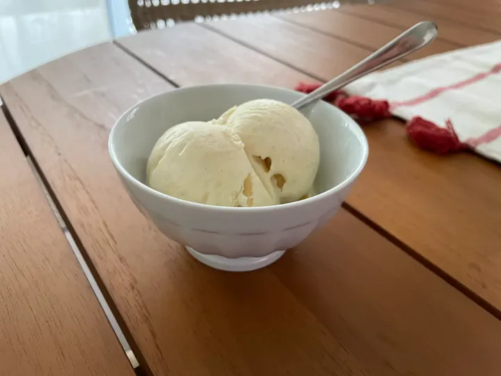 Two scoops of white ice cream in a bowl on a wooden table