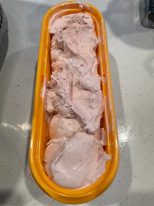 Pale pink ice cream in a long yellow loaf tin