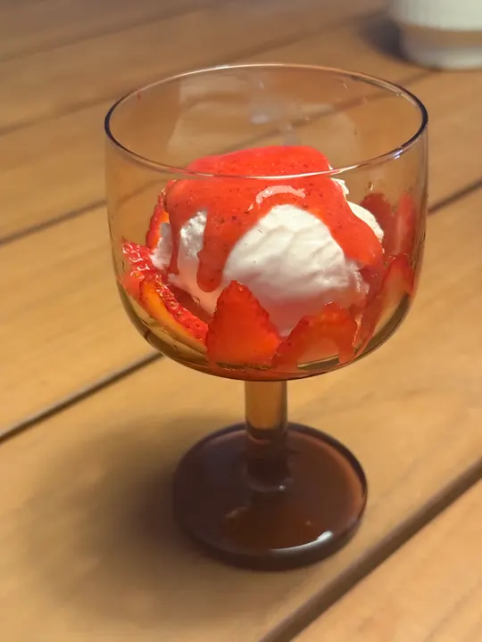 The sundae finished with bright red strawberry sauce poured over the ice cream