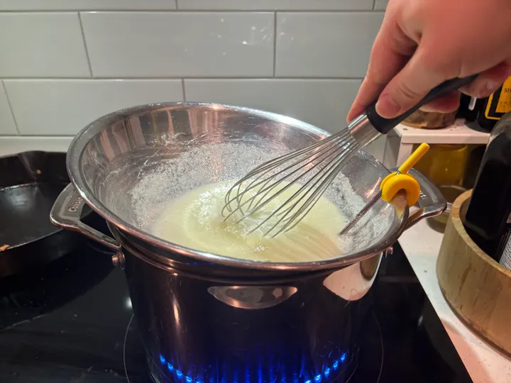 Whisking egg whites and sugar in a steel bowl over a pan of simmering water, on the element