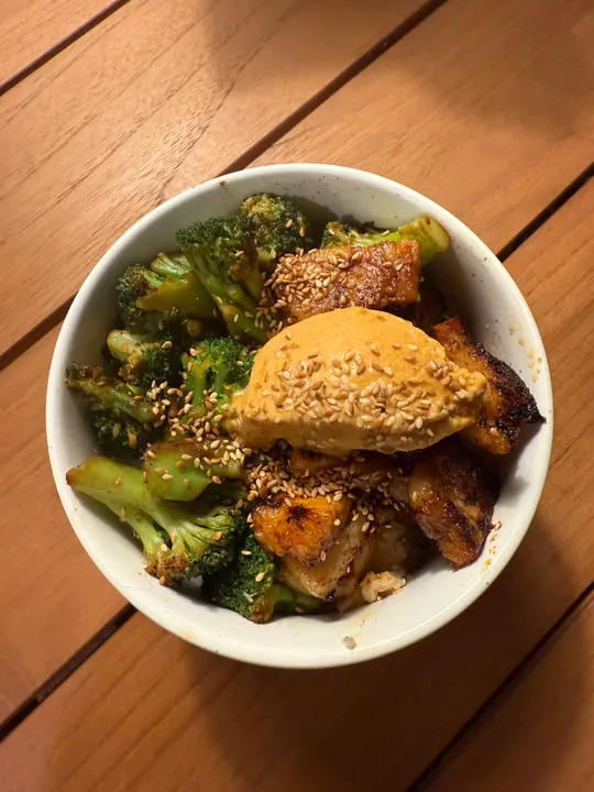 Rice bowl with glazed pork belly and broccoli, topped with a quenelle of gochujang-persimmon ice cream and sesame seeds